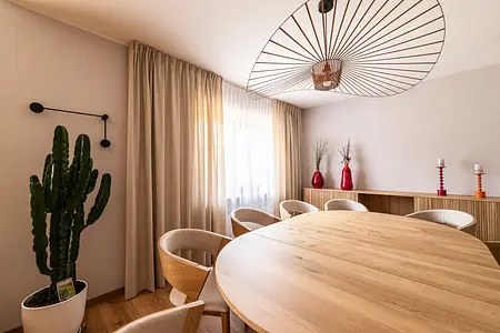 Wnętrze jadalni z okrągłym stołem, drewnianymi krzesłami i roślinami. Styl boho, industrialny i skandynawski.