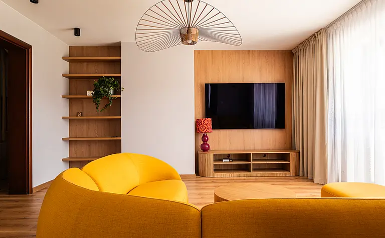 Wnętrze salonu w stylu boho, eklektycznym, nowoczesnym z żółtą sofą i drewnianymi akcentami.