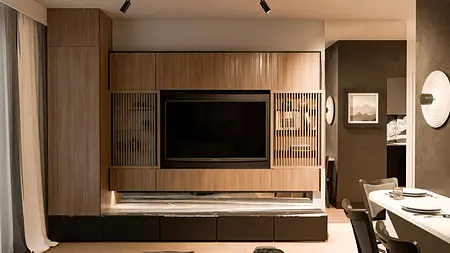 Nowoczesne wnętrze z minimalistyczną zabudową drewnianą i telewizorem.