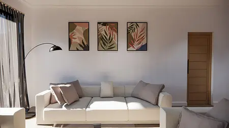Wnętrze salonu z białą sofą, czarną lampą i obrazami roślinnymi.