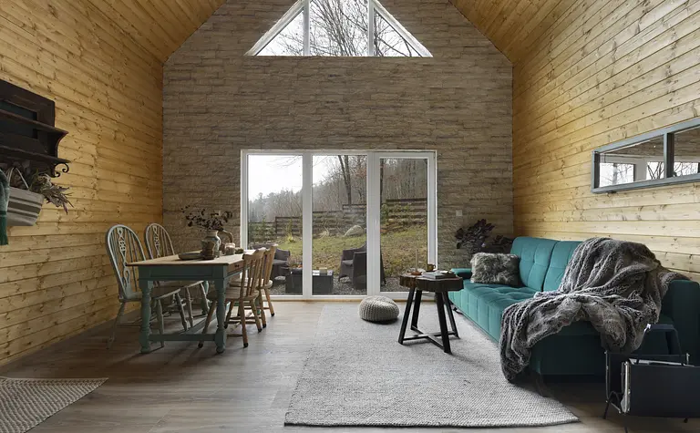 Rustykalne wnętrze z zieloną sofą i drewnianym stołem, naturalne światło.