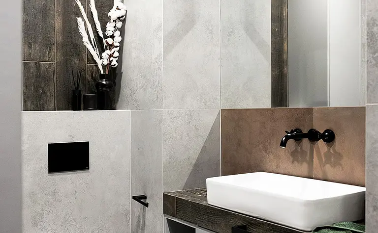 Nowoczesna łazienka z szarymi płytkami i czarnymi detalami, styl industrialny.