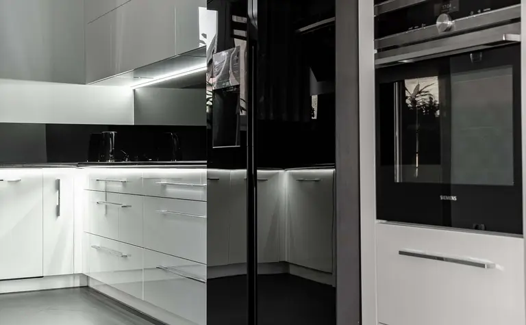 Nowoczesna kuchnia z białymi meblami i czarnym sprzętem, minimalistyczny design.