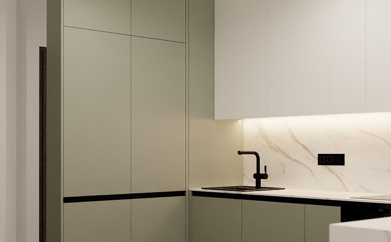 Kuchnia z nowoczesnymi zielonymi meblami, białym blatem i czarnymi akcentami.