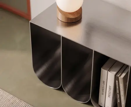Szara metalowa konsola z lampą i książkami w salonie, styl nowoczesny, soft minimalizm, współczesny