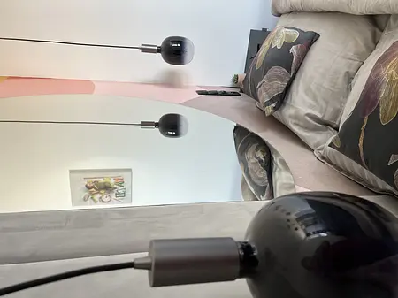 Wnętrze sypialni z nowoczesnymi lampami i eleganckimi poduszkami w stylu quiet luxury.