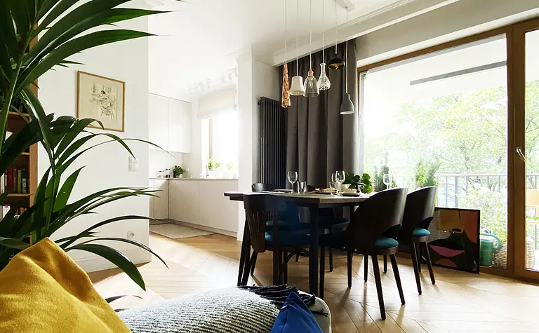 Wnętrze jadalni z minimalistycznym designem, drewnianym stołem, kolorowymi poduszkami.