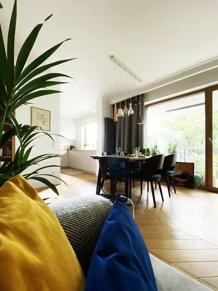 Wnętrze jadalni z minimalistycznym designem, drewnianym stołem, kolorowymi poduszkami.