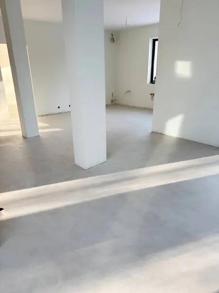 Przestronny pokój z białymi ścianami, szarym podłogą, w stylu art deco i minimalistycznym.