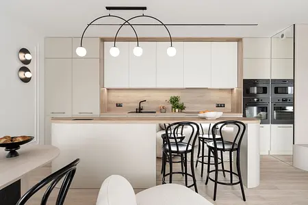 Współczesna kuchnia z białymi meblami i drewnianym blatem, nowoczesne oświetlenie