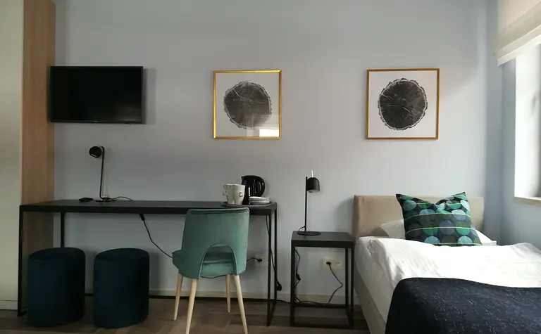 Wnętrze pokoju z biurkiem, telewizorem i łóżkiem w stylu minimalistycznym, nowoczesnym, współczesnym.