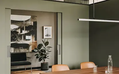 Wnętrze jadalni z drewnianym stołem, zielonymi ścianami i rośliną w doniczce, styl industrialny, nowoczesny, vintage.