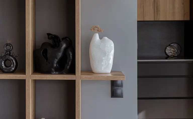 Minimalistyczne wnętrze z półkami i nowoczesnymi dekoracjami ceramicznymi.