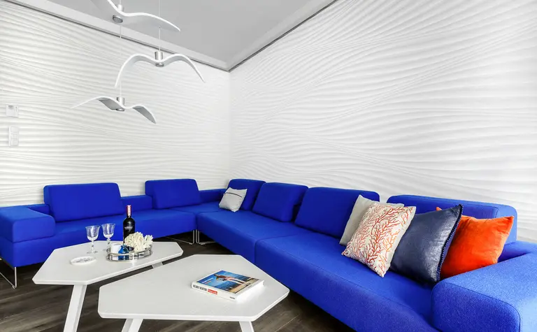 Nowoczesny salon w stylu skandynawskim z niebieską sofą i białą ścianą.