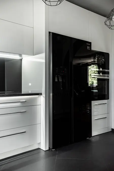 Nowoczesna kuchnia z białymi meblami i czarnymi akcentami, minimalistyczny design.