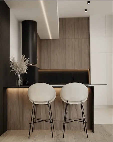 Wnętrze kuchni z drewnianym blatem, jasnymi krzesłami i nowoczesnym oświetleniem.