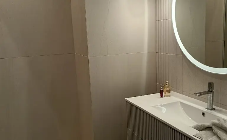 Wnętrze nowoczesnej łazienki z umywalką i dużym lustrem.