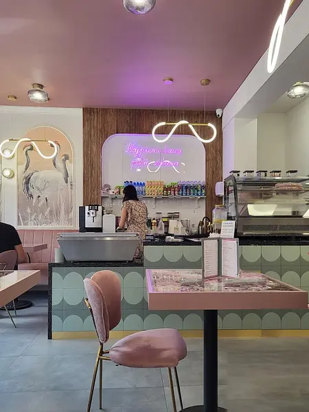 Wnętrze kawiarni z różowymi krzesłami i zielonymi płytkami, styl art deco i quiet luxury.
