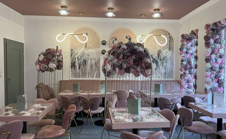 Wnętrze kawiarni z dekoracjami w stylu art deco i quiet luxury, pełne kwiatów.