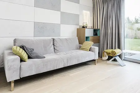 Wnętrze salonu w stylu minimaluxe z szarym sofą i drewnianymi akcentami.