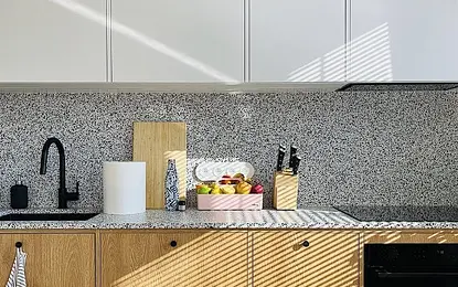 Kuchnia minimalistyczna z drewnianymi meblami i owocami na blacie.