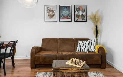 Wnętrze salonu w stylu vintage z brązową sofą, drewnianym stolikiem do gier i dekoracjami.
