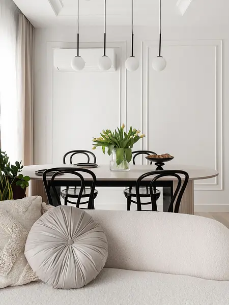 Wnętrze jadalni z okrągłym stołem, czarnymi krzesłami i wazonem z tulipanami, styl współczesny.