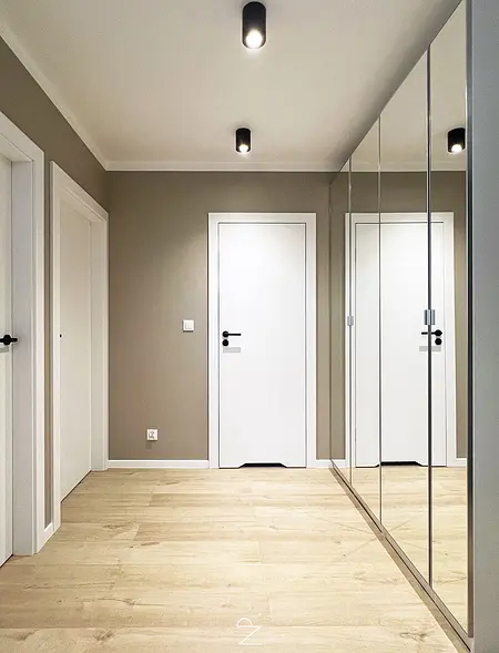 Przedpokój w stylu minimalistycznym z lustrami i jasnym drewnem