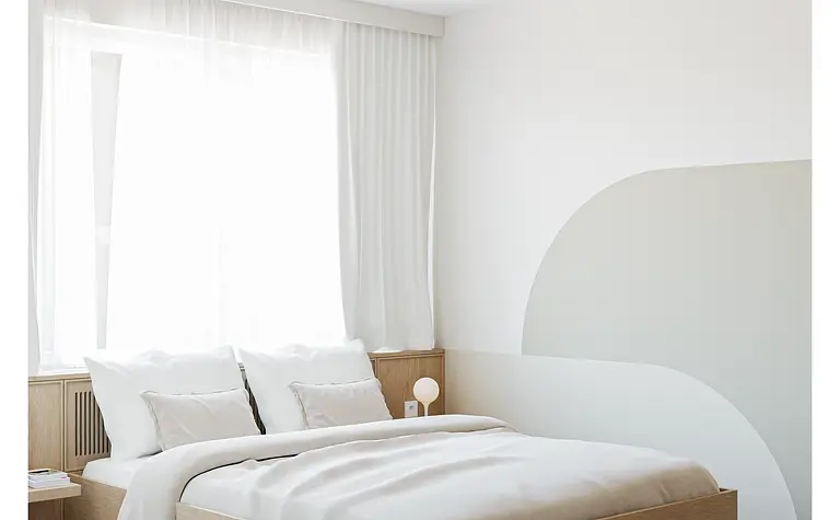 Wnętrze sypialni w stylu japandi z minimalistycznym łóżkiem i nowoczesnymi detalami.