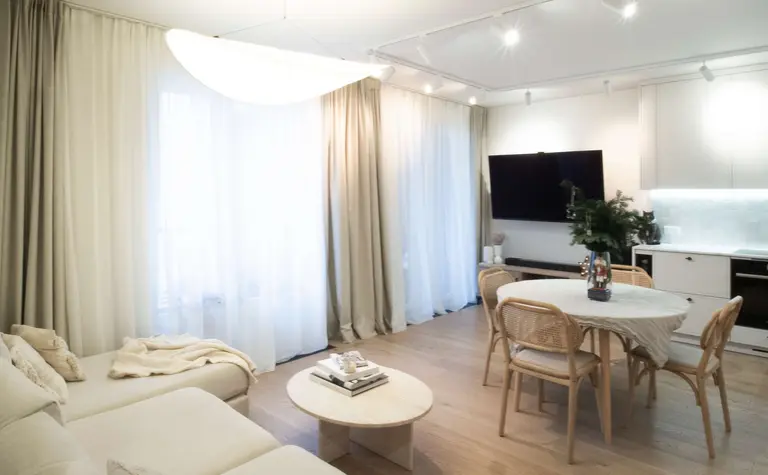 Wnętrze salonu z jasnymi zasłonami i drewnianym stołem, styl quiet luxury.