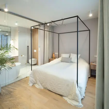 Sypialnia z łóżkiem, drewnianymi detalami i strefą łazienki w stylu quiet luxury.
