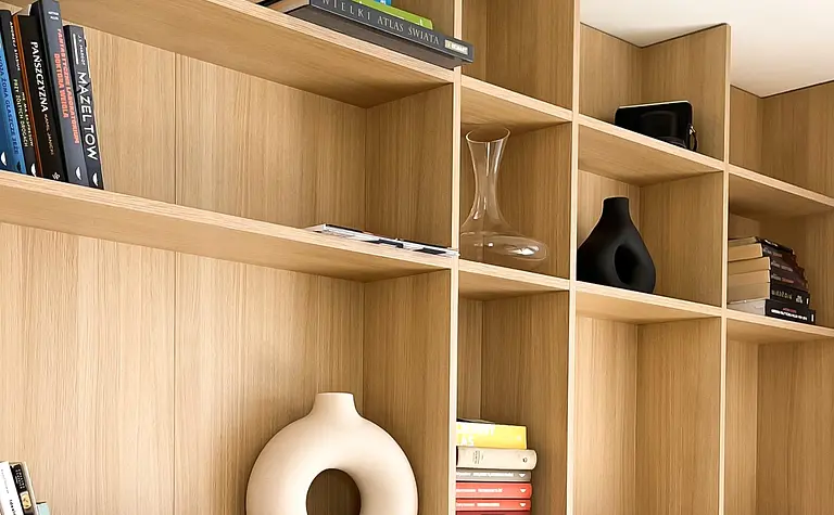Minimalistyczne wnętrze z półkami, książkami i dekoracjami w stylu soft minimalizm.
