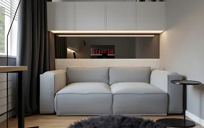 Minimalistyczne wnętrze z szaro-skalną sofą i czarnymi akcentami.