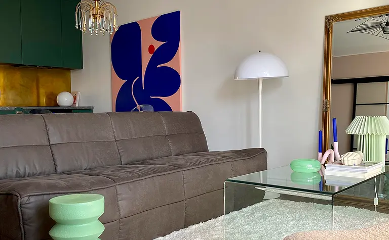 Wnętrze salonu z brązową sofą, zielonym stolikiem i nowoczesnymi akcentami.