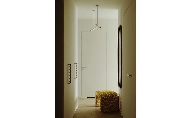 Przedpokój w stylu industrialnym i minimalistycznym z białymi ścianami i żółtym pufem.