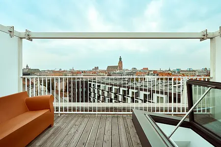 Taras z minimalistycznym wystrojem, pomarańczowa sofa i współczesne detale.