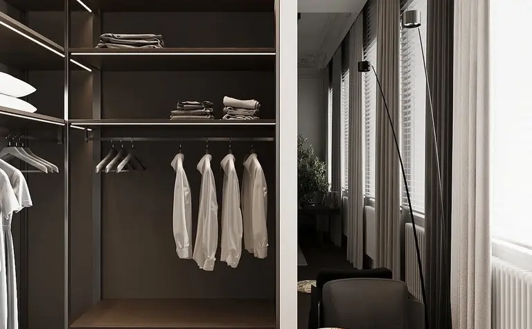 Garderoba minimalistyczna z drewnianymi półkami, nowoczesnym fotelem i dużymi oknami.