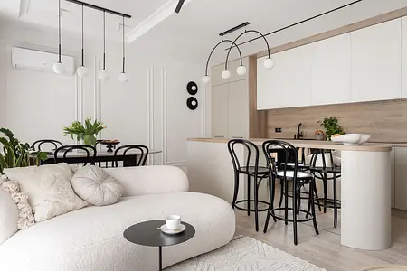 Wnętrze nowoczesnej kuchni z białymi meblami, drewnianym blatem i roślinami.