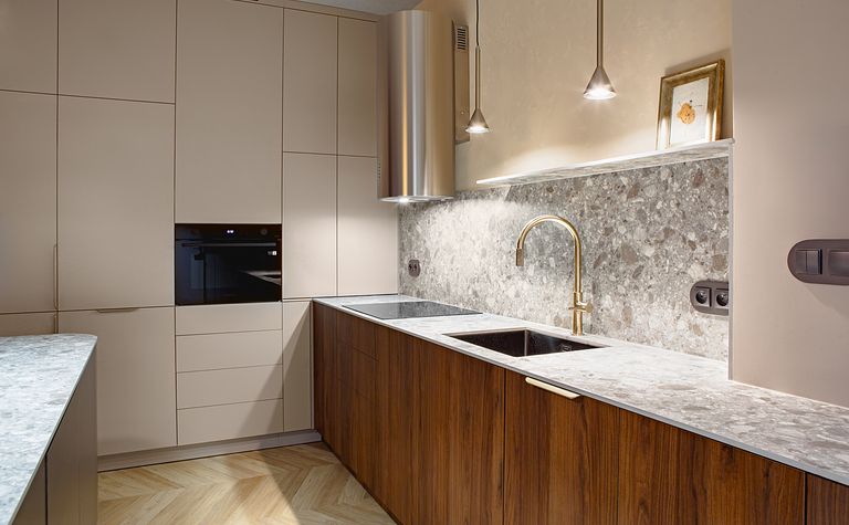 Nowoczesna kuchnia w stylu art deco i industrialnym z brązowymi meblami i marmurowym blatem.