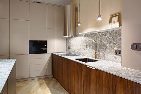 Nowoczesna kuchnia w stylu art deco i industrialnym z brązowymi meblami i marmurowym blatem.