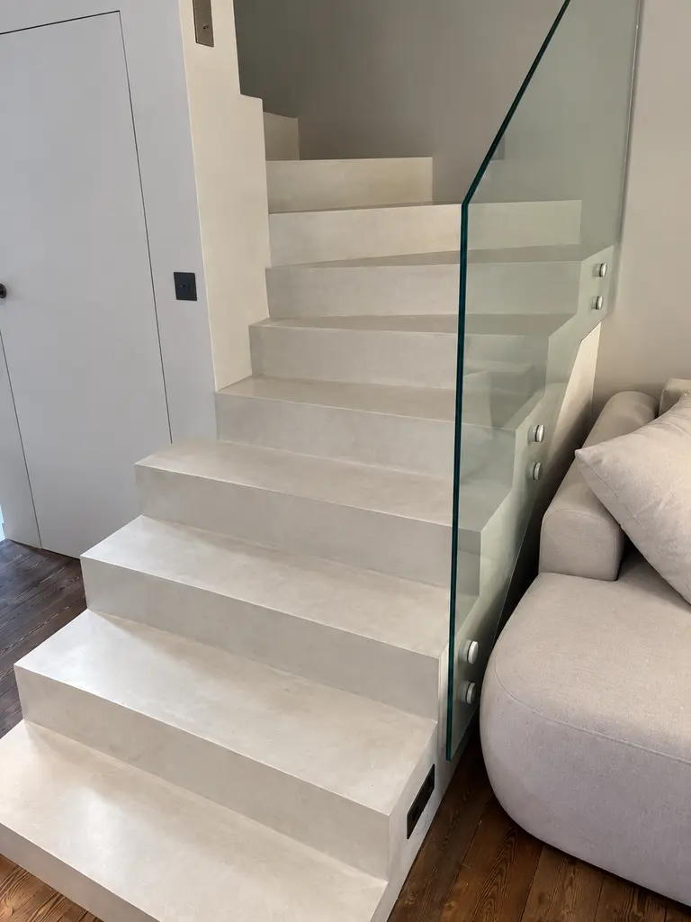 Schody w stylu art deco i minimalistycznym z białymi stopniami i szklaną balustradą.
