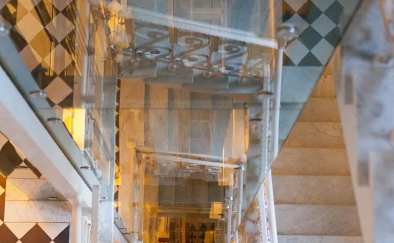 Schody z eklektycznym i współczesnym wystrojem, czarno-biała podłoga i szklane balustrady.