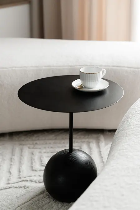 Nowoczesny stolik kawowy z czarnym blatem i filiżanką na białym tle.