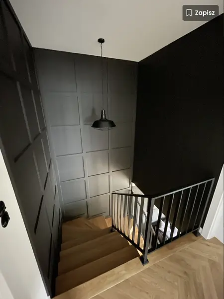 Widok schodów z drewnianymi stopniami i czarną ścianą, styl dopamine decor