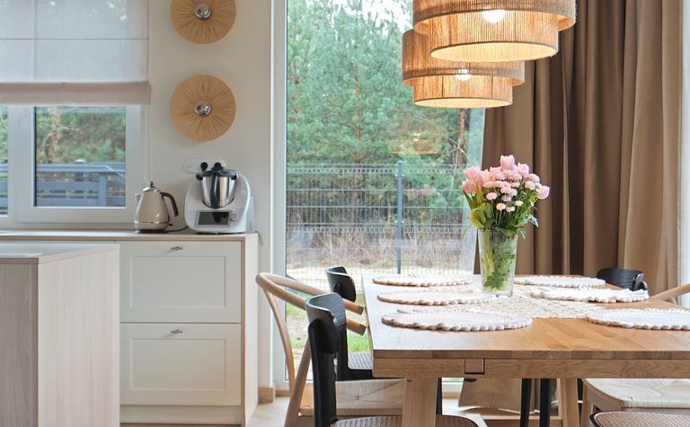 Wnętrze jadalni w stylu rustykalnym i boho z drewnianym stołem.