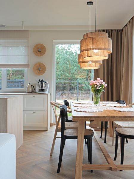 Wnętrze jadalni w stylu rustykalnym i boho z drewnianym stołem.