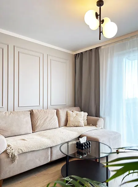 Wnętrze salonu z minimalistycznym stylem, komfortowa sofa, szklany stół, zasłony.