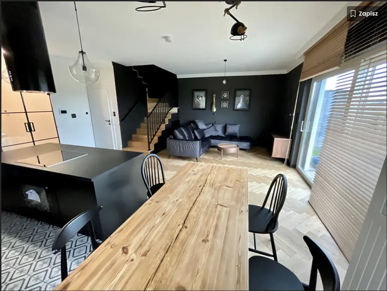 Wnętrze kuchni w stylu dopamine decor z czarnymi meblami i drewnianym stołem.