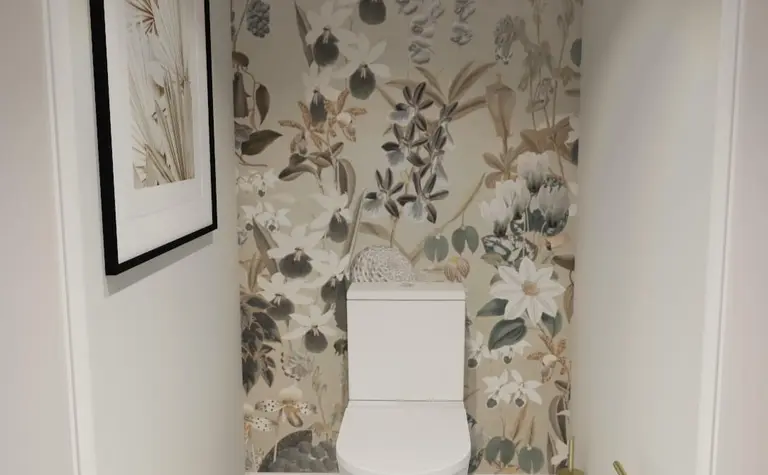 Toaleta z białą ceramiką, kwiecistą tapetą w stylu prowansalskim, czarno-biała podłoga.