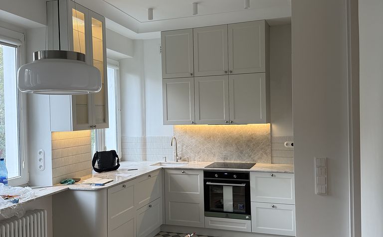 Jasna kuchnia modern retro z kamiennym blatem w mieszkaniu w kamienicy